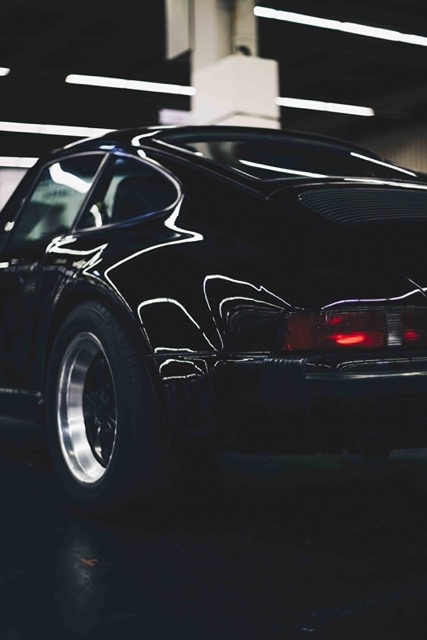 vertical-shot-of-a-parked-black-car-with-a-blurry-Porsche 928