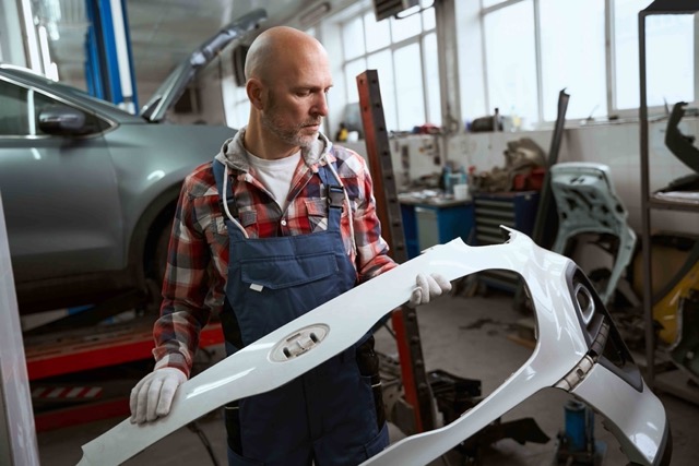 middle-aged-man-holds-and-examines-a-car-bumper-Porsche 928
